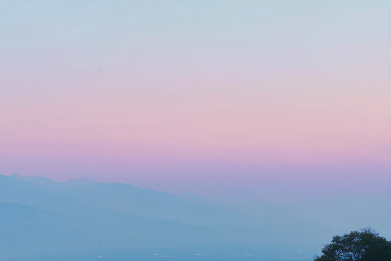 山の夕暮れ空のおしゃれ背景｜柔らかいピンク色の空と山の輪郭が美しいシーン。静かな夕暮れ時の風景が、シンプルでありながらも洗練された「おしゃれ背景」を作り出し、心に残る落ち着きのある空間です。