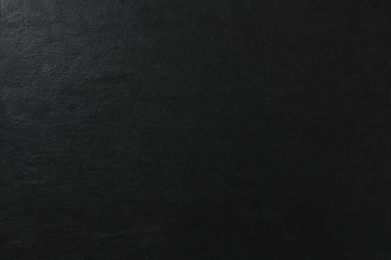 黒い背景で静かな深みのある壁面｜深い黒色が一面に広がり、わずかな光の反射が壁面に陰影を与えているシンプルな背景。上品で落ち着いた雰囲気を醸し出し、「黒」の背景が視覚的に存在感を放っている。シンプルながらも深みを感じさせる。