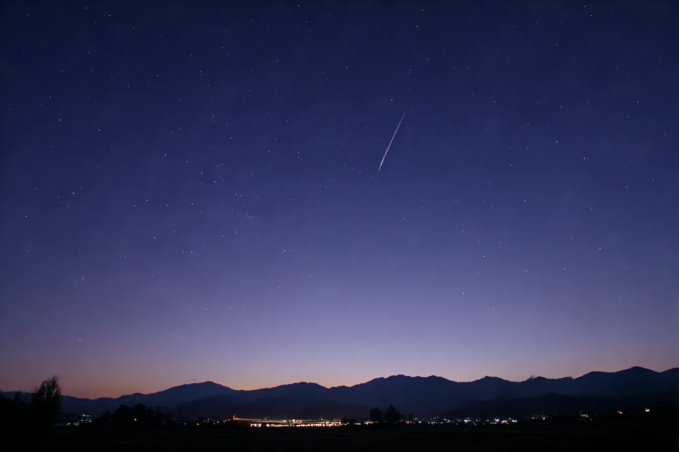 儚い背景・星空と流れ星の夜｜星のまたたきと流れ星が映える澄んだ夜空の背景。深い群青と地平線の光が対比を生み、静寂と幻想が同居する儚い世界観。