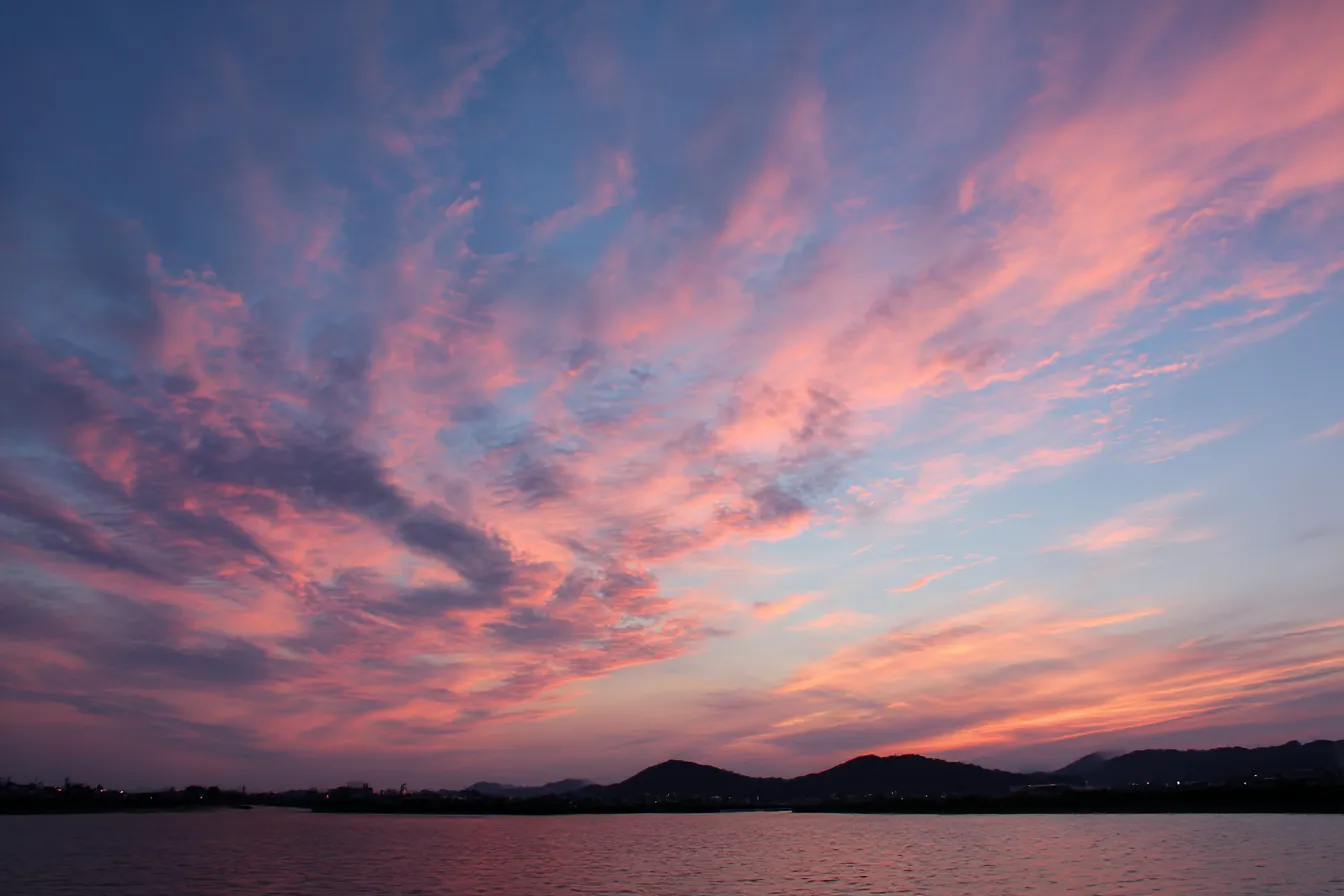 夕焼け背景×湖畔と広がる雲｜水面に映える空とゆったり広がる雲が、静寂と感動を感じさせる構図。淡いパープルピンクの色彩が穏やかな感情を引き出し、日常系や回想演出にマッチします。