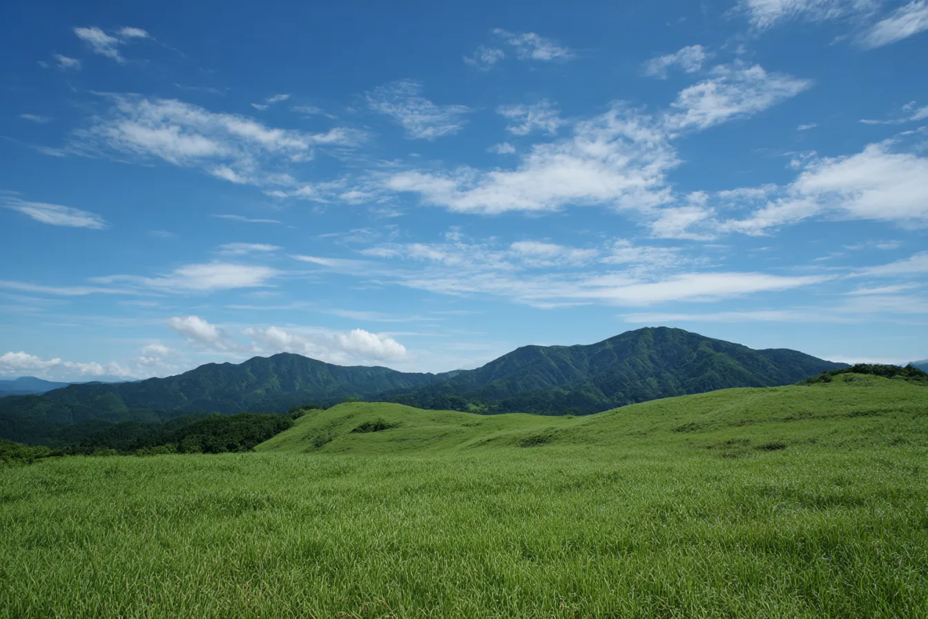 草原背景　夏の山岳草原と青空｜緑豊かな高原の草原が広がる中、奥には山並みが連なる爽快な景観背景。空の青と草の緑が鮮やかで、自然の広大さと清涼感が伝わる。