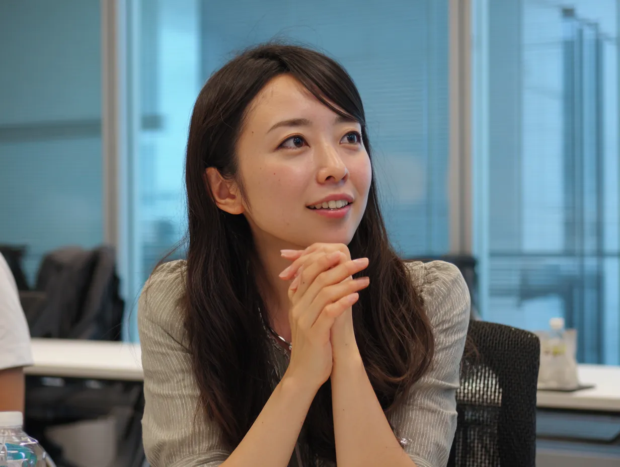 憧れを見つめる女性社員｜優しい眼差しで遠くを見つめる女性の表情が印象的。自然光に包まれた会議室の一角で、穏やかに佇む姿が憧れという感情を静かに語りかけてくる一枚。