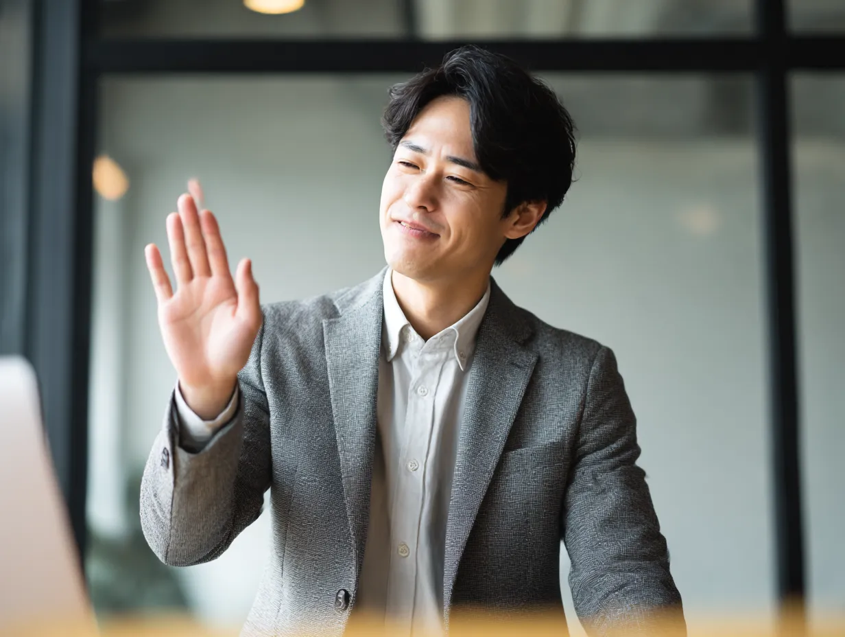 バツの代替演出となる手上げ構図｜やや笑顔の男性が手のひらを上げる仕草をとらえた明るい構図。バツほど強くなくても意思を示せるジェスチャーとして、フレキシブルな用途に対応する。