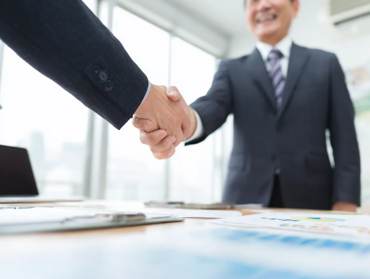 力強い握手を交わすビジネスの商談｜前景でしっかりと握手を交わすビジネスマンの手元を強調した構図。意思決定の瞬間や「商談」の最終合意を象徴する力強い一枚。