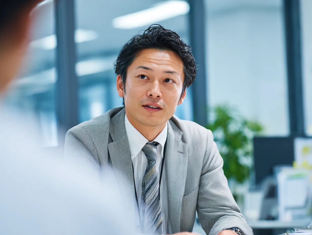 提案を語る真剣な課長の表情｜会議中にしっかりと話す若手課長の姿。オフィスの明るさと清潔感が伝わる構図で、前向きで行動的な印象を与えます。
