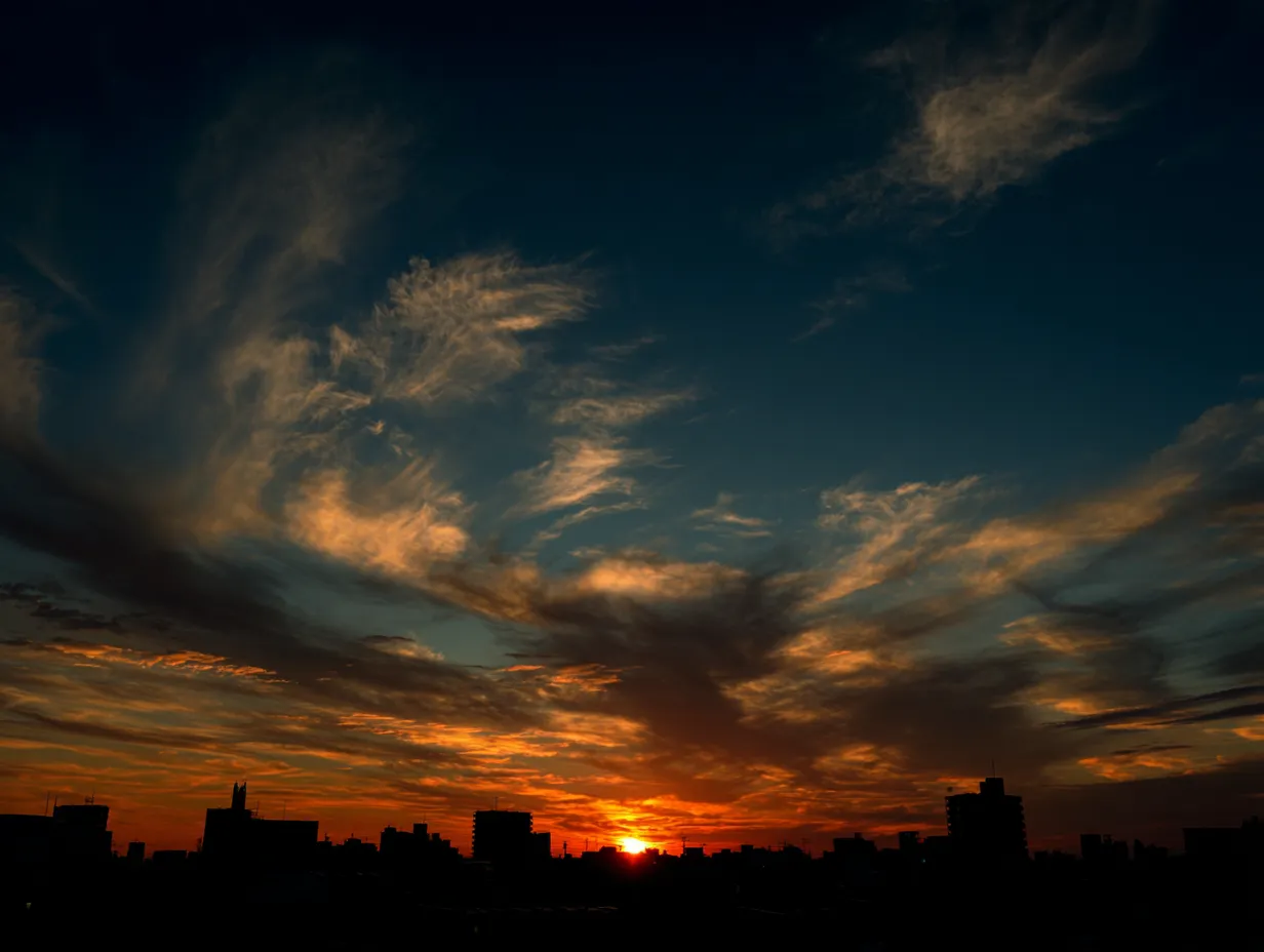 エモい空と赤く燃える夕暮れ｜街並みのシルエットと真っ赤に燃えるような夕暮れが映えるエモい空の写真です。雲の動きと空のグラデーションが印象的で、情熱や活力を表現するビジュアルにぴったりです。