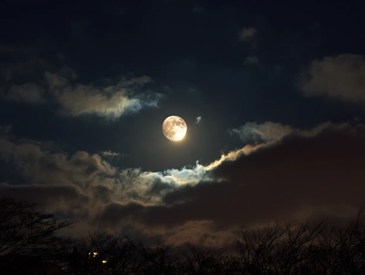エモい夜の満月写真｜雲の合間に浮かぶ満月が印象的なエモい夜の素材です。光の広がりと雲の質感が調和し、神秘的なムードを伝えるデザインに役立ちます。