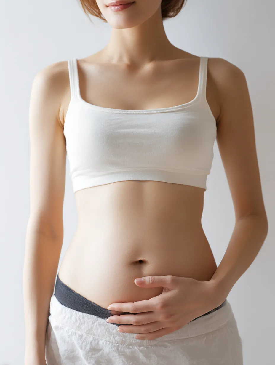 妊娠二ヶ月のおなかの姿｜正面から描かれた女性が、片手で妊娠二ヶ月のおなかを支える。わずかな丸みを帯びた腹部が画面に収まり、静かな気配と生命の気配が共鳴している。
