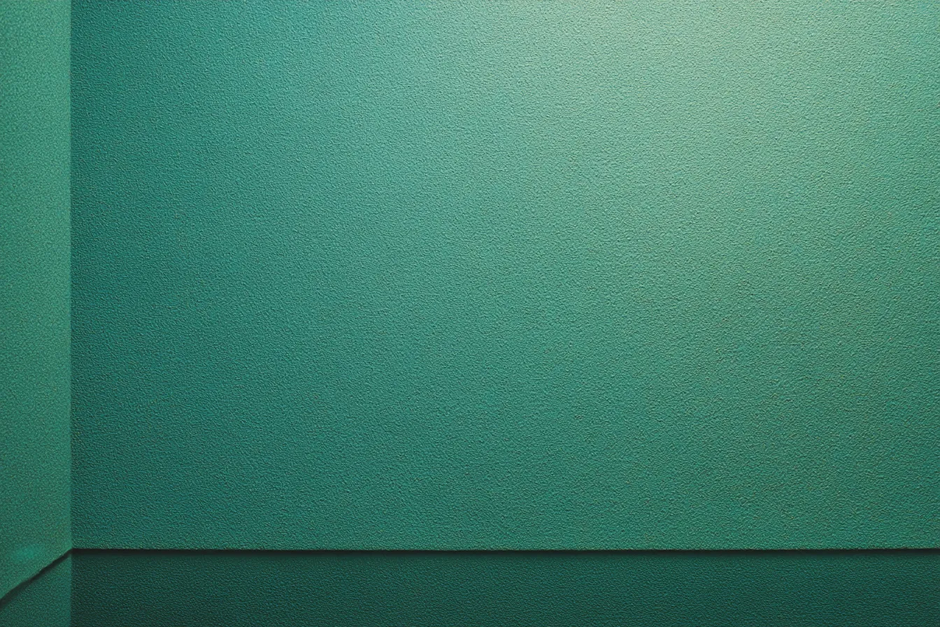 エメラルドグリーン背景の壁面｜荒い質感の塗装壁が面で構成され、落ち着いたトーンのエメラルドグリーン背景が視覚に安定感を与える無機質な素材。空間に静けさと冷静さを演出する用途に適しています。