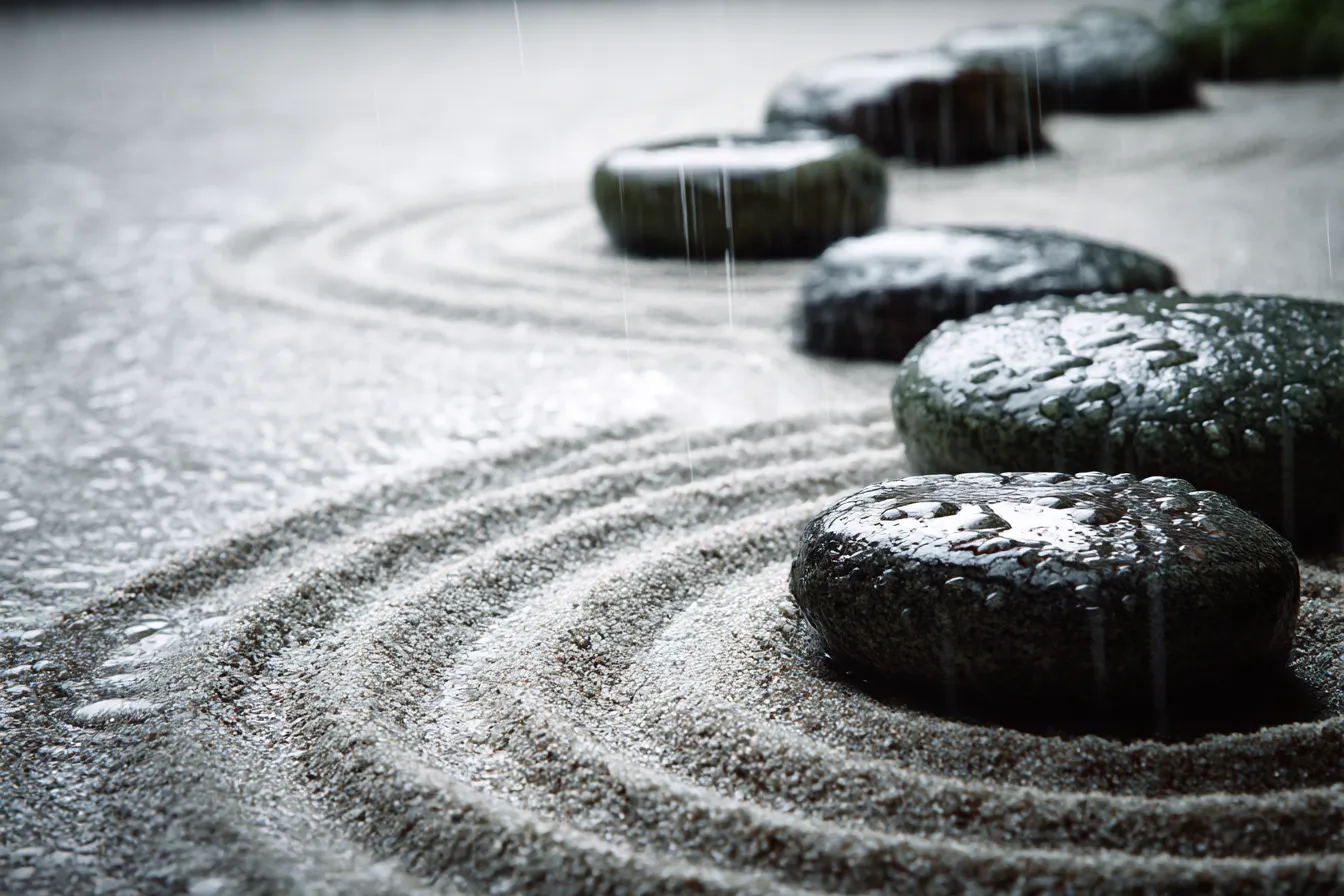 銀色の石と砂の背景｜雨に濡れた石が銀色に光る砂浜。石の輪郭が滑らかな曲線を描き、雨粒が弾ける中で銀色の輝きが一層引き立ちます。このシンプルな景色が、静かな落ち着きを与え、自然の美しさを感じさせます。