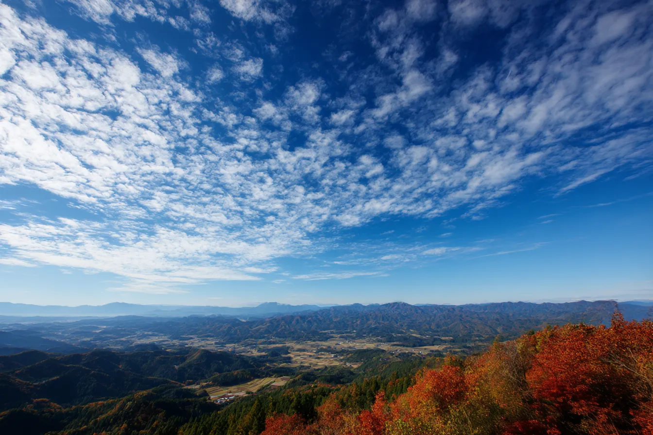 秋の雲・写真に映る高原と巻雲の空｜鮮やかな青空に広がるうろこ雲と紅葉の山肌が、遠景に向かって広がる立体的な構図で展開。空の美しさと地形の広がりが際立ち、爽快な秋の空気感を伝える。
