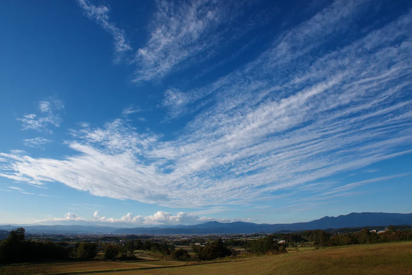 秋の雲・写真に映る平野と筋状の雲｜広大な平野の上空を覆う筋状の秋雲が、遠近感のある構図で印象的に描かれている。空の奥行きと爽やかさが写真ならではのリアルさで表現されている一枚。