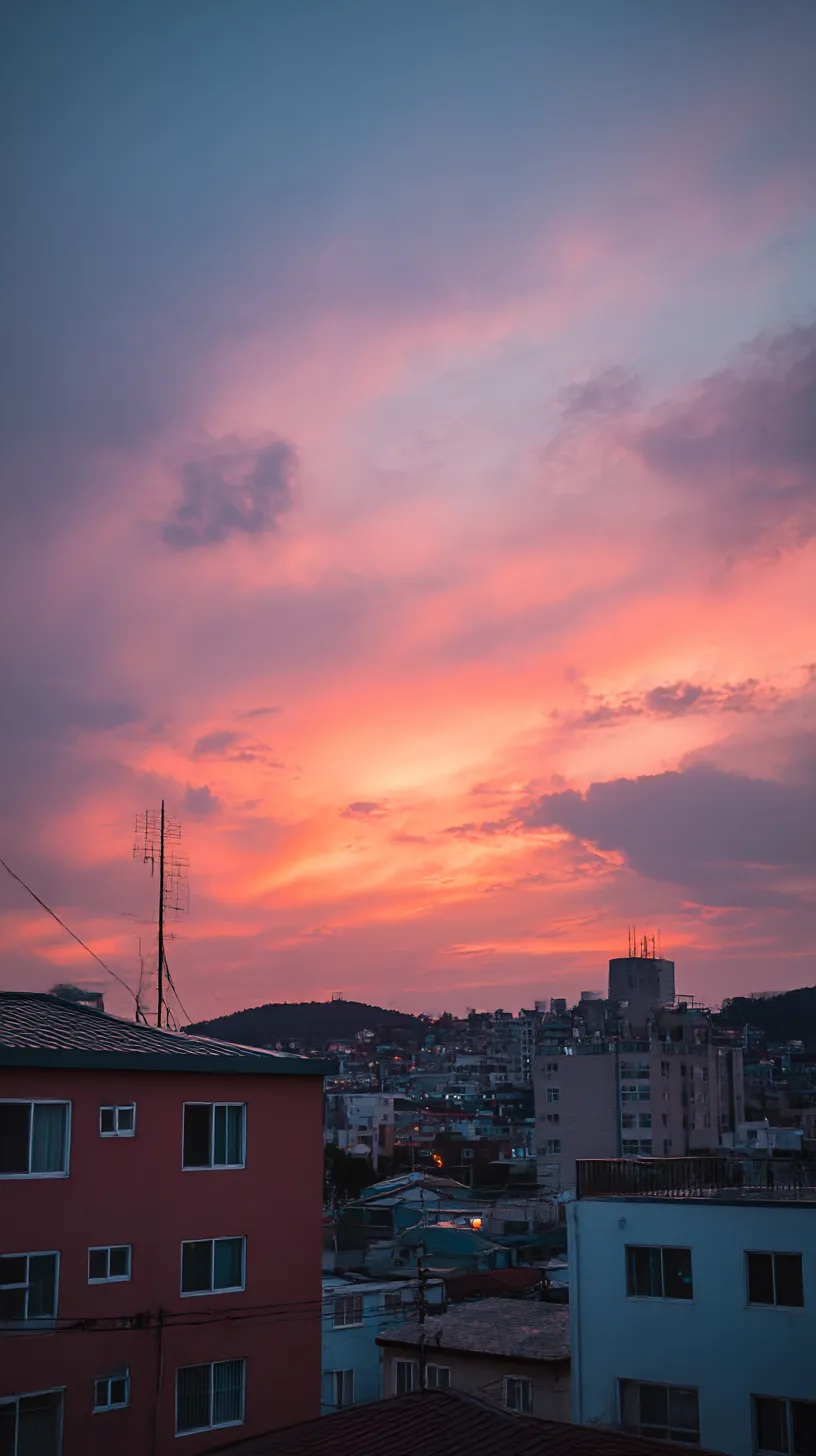 エモい韓国壁紙 茜雲の下で｜燃えるような茜色の雲が街並みを覆い、住宅街の屋根に淡い光を落とすエモい韓国壁紙。空と街のコントラストが日常と非日常の狭間を感じさせる。
