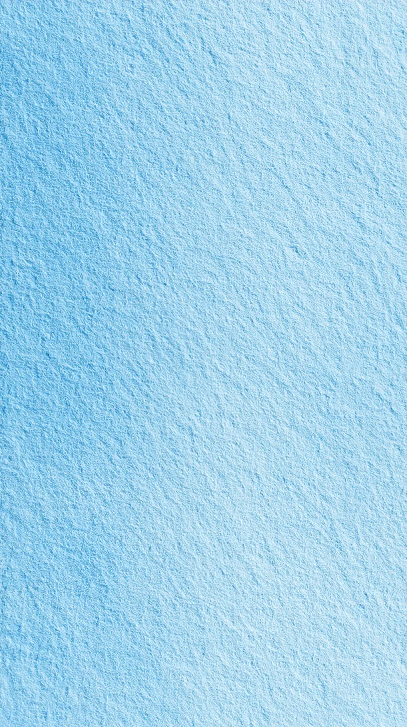 水色の無地壁紙 透き通る光｜水色の無地壁紙は、淡い色調と均一な表面が透き通るような光の広がりを見せる。控えめな影がリズムを生み、静謐でありながら空間全体に透明感を与える表現となっているのが特徴的である。