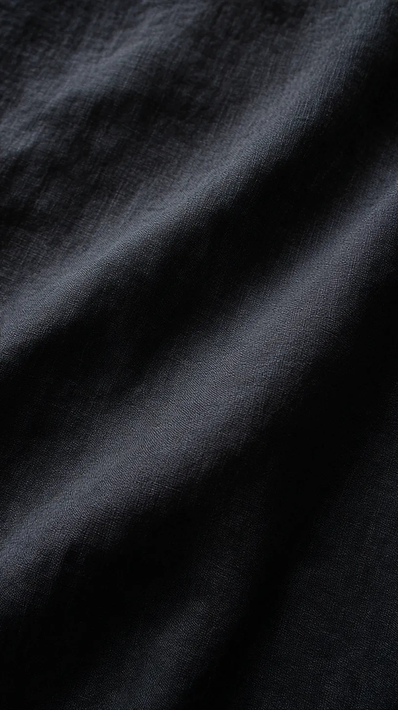 黒のシンプル壁紙 柔布のきらめき｜黒のシンプル壁紙は、布のようにしなやかに波打つ質感を持ち、光を受けて柔らかくきらめく。繊細な凹凸が自然な陰影を描き出し、静謐な雰囲気を漂わせている。