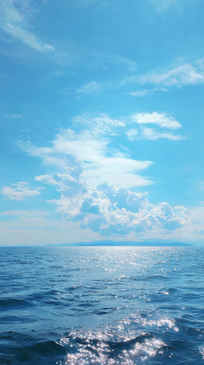 空壁紙 水面の煌めき｜果てしない水平線に太陽光が反射し、海面が宝石のように光る空壁紙。淡い雲と鮮やかな水面が調和し、爽やかな清涼感を与えます。光の粒がリズミカルに広がり、透明感のある空気感を強調しています。